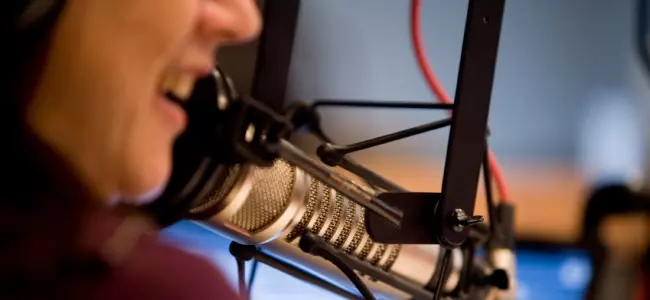 Close-up of a radio host speaking into a professional studio microphone, symbolizing the role of radio in music promotion and artist marketing.